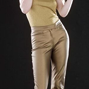 Ruth Kemmer model wearing gold trousers and top applying blusher to her face with a brush