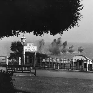 A salvo of bombs dropping into the sea off a South East coast town during Second World