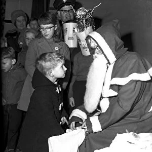 Santa Claus gives a little boy a present at St. John Ambulance bazaar, Holyhead Road
