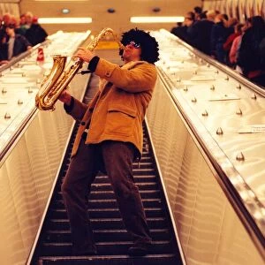 Sax player Jason Tenniswood in a wig entertains travellers at Monument Metro station
