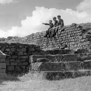 Schoolchildren sitting on the wall of the Roman Granary at Housesteads Fort in Schoolchildren sitting on the wall of the Roman Granary at Housesteads Fort in