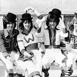 Scottish pop group The Bay City Rollers, sitting on a bench Wearing bowler hats
