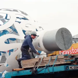 The sculpture Bottle of Notes is lifted off its low loader in the Central The sculpture Bottle of Notes is lifted off its low loader in the Central