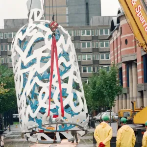 The sculpture Bottle of Notes is lifted off its low loader in the Central The sculpture Bottle of Notes is lifted off its low loader in the Central