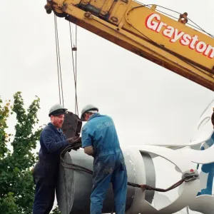 The sculpture Bottle of Notes is lifted off its low loader in the Central The sculpture Bottle of Notes is lifted off its low loader in the Central