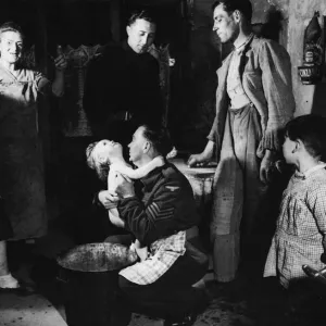 Sergeant Ted Okey helps a French woman bathe her child whilst Tommy Dalby talks to Sergeant Ted Okey helps a French woman bathe her child whilst Tommy Dalby talks to
