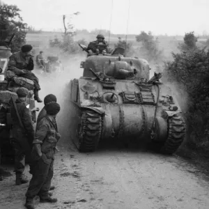 Sherman tanks pass other tanks and crew waiting for the order to advance on Caen Sherman tanks pass other tanks and crew waiting for the order to advance on Caen