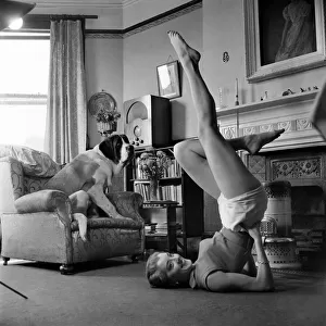 Shirley Burke doing stretching exercises in the living room of her home with her pet St