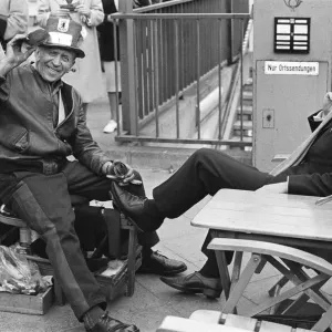 A Shoe Shine goes to work on a clients shoes close to the underground station