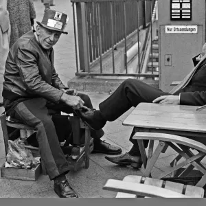A Shoe Shine goes to work on a clients shoes close to the underground station