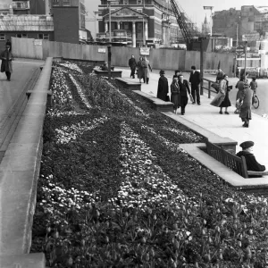 Shoppers enjoy the spring sunshine and the flower beds outside Holy Trinity Church