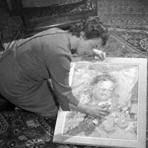 Sibylle Cole cleans a portrait she painted of her son. Glass negs taken January 1959