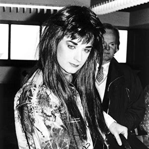 Singer Boy George wearing a long wig and a coat covered with safety pins