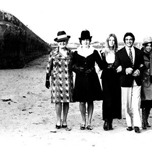 Singer Frankie Vaughan strolling along the beach with some of the models from a fashion