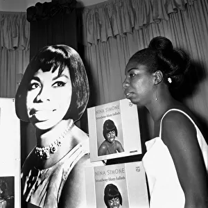 Singer Nina Simone stands besides a poster advertising on of her records at a press