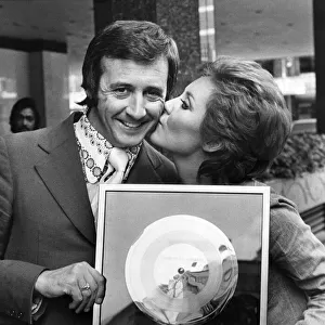 Singer Tony Christie receives a kiss from Lulu who presented him with his gold disc in