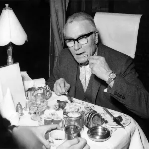Black and white print of a man eating breakfast on a train