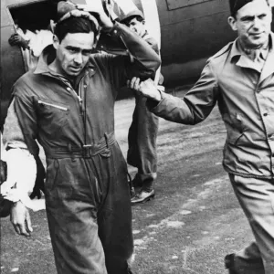 A slightly wounded and shaken waist gunner is led from his place by his flight surgeon
