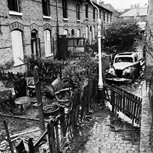 Slum housing in Birmingham. Burnt out car in the alleyway behind derelict houses