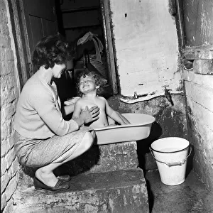 Slum housing, Ellison Street, Liverpool. Two-year-old Jean Ann Jameson takes a bath