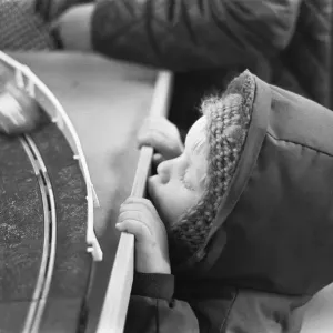 El pequeño niño mira con nostalgia el último conjunto de carreras de coches a escala en slot Scalextric en la caja del juguete.