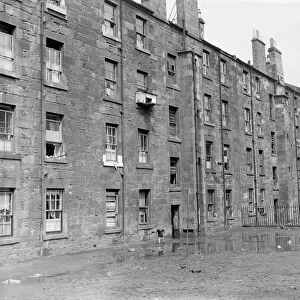 A small boy plays in the squalor outside tenement blocks in Govan, Glasgow