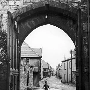 A small boy walks through the archway at the entrance of Ruthin Castle Denbighshire