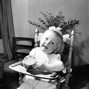 Small girl enjoying a cup of tea. August 1953 D5235-002