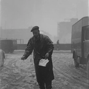 Snow scenes in London - Man springling salt on snow in Fetter Lane DM