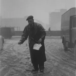 Snow scenes in London - Man springling salt on snow in Fetter Lane DM