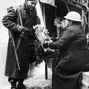 Soldier buying flowers from well protected flower seller during WW2
