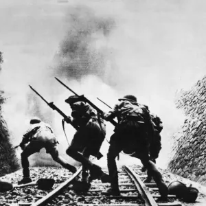 Soldiers of the British Eighth Army charge through a railway cutting with fixed bayonets