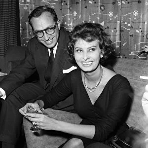 Sophia Loren (with an un-named man) pictured sitting in a chair at London Airport