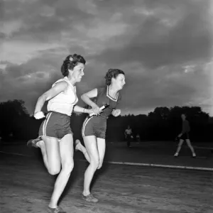 Sport Athletics: Jean, farthest from camera, taking the baton from Jean Foulds in a Sport Athletics: Jean, farthest from camera, taking the baton from Jean Foulds in a