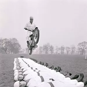 Stunt team in action 1966. Man leaps on a motorcycle over men lying on the ground