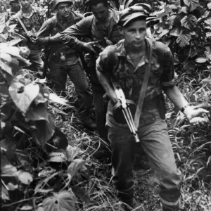 A sub-machine gun in one hand and a grenade in the other