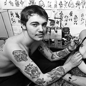 Tattooist John Taylor, 16, from Kings Lynn tattooing Della Gilbert, 20. 1st July 1978