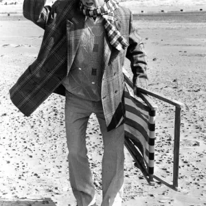 Television comedian Norman Colliercarrying a deckchair on the beach April 1991