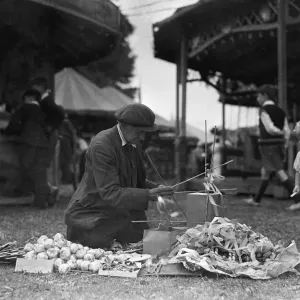 A toddler looks on in curiosity as a fancy goods vendor prepares his goods for sale