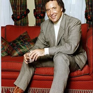 Tom Jones British Singer Sitting on a red couch Holding a glass
