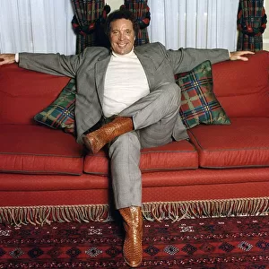 Tom Jones entertainer singer sits on sofa setee