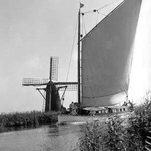A traditional Norfolk Broad yachts sailing past one of the many windmill water pumps that A traditional Norfolk Broad yachts sailing past one of the many windmill water pumps that