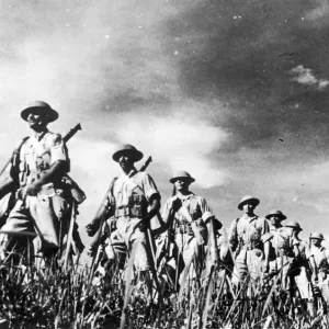 troops of a famous Indian regiment advancing in column through countryside in Malaya