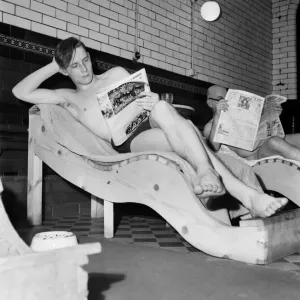 Turkish bath assistant Ernest Smith reading his newspaper. January 1953 D259