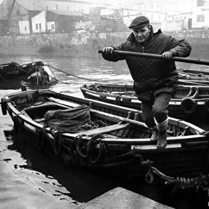 A Tyne foyboatman, member of a dying trade, ties up his boat alongside others at