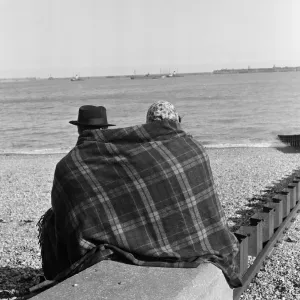 Two visitors to Dover in Kent huddled up on the beach in blankets. 16th April 1954 Two visitors to Dover in Kent huddled up on the beach in blankets. 16th April 1954