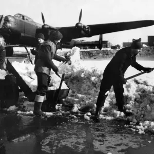 Warmly clad members of Ground Crew clearing away snow from a dispersl point at a bomber