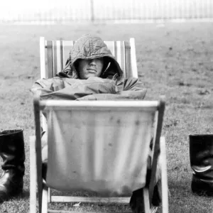 A weary traveller removes his boots as he takes a rest on a bed made from two deckchairs
