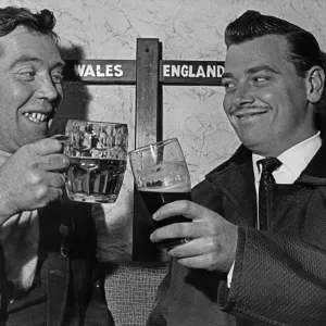 A black and white print of two men clinking glasses in a hotel lounge A black and white print of two men clinking glasses in a hotel lounge