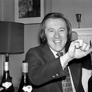 Wine: Mr. David Frost trying to open a bottle of wine at his home. March 1975 75-01338
